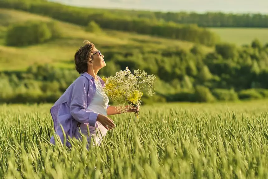 Elderly woman in stylish clothing relaxing in a lush meadow, embodying the fulfilling experiences