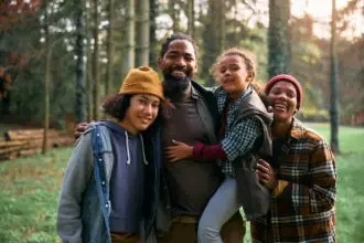 Happy black family enjoying in camping weekend in the woods and looking at camera.